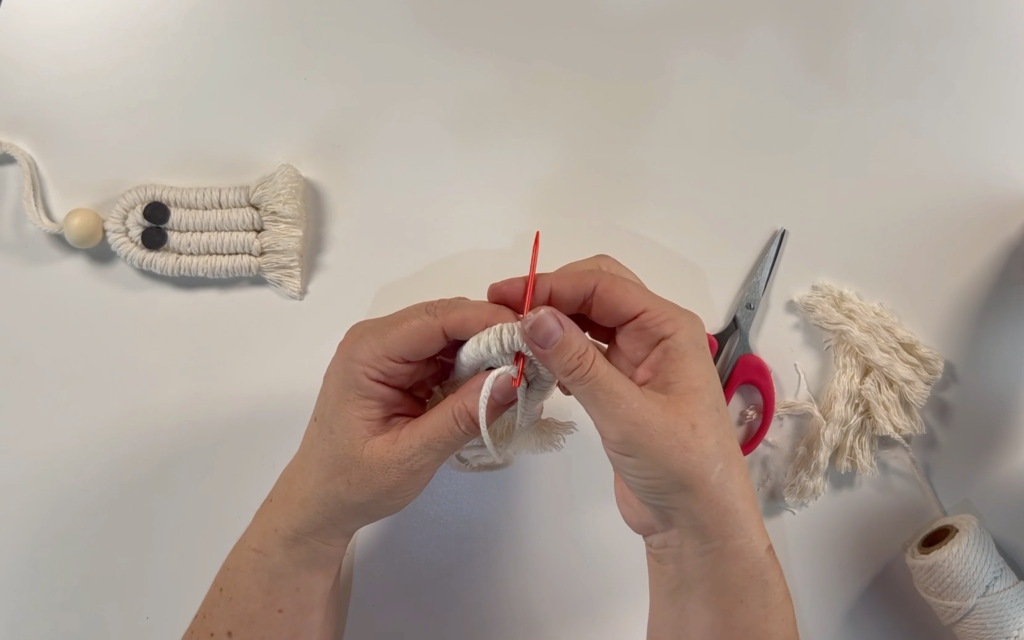 Threading 3mm macrame cord through the top of the macrame ghost using a large eye needle.