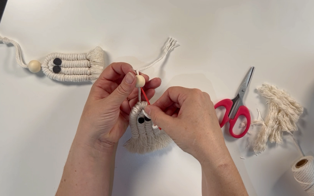 Threading a bead onto the 3mm macrame cord using a large eye needle